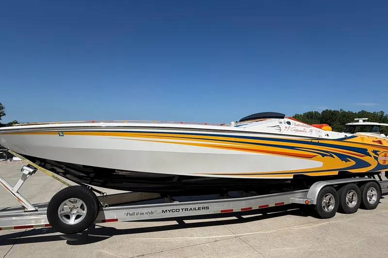 Slide: The Image of 2002 Cigarette 35' Cafe Racer boat on trailer, vibrant yellow and blue design. - 6