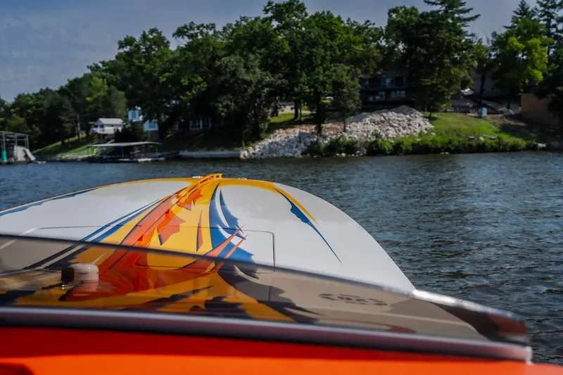 Slide: The Image of 2002 Cigarette 35' Playboy Edition boat on a scenic lake with vibrant graphics. - 24