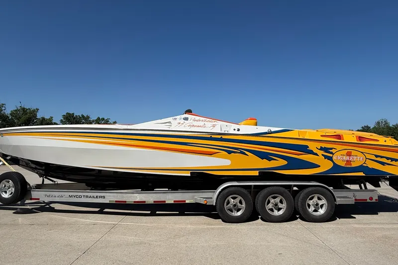 Slide: The Image of 2002 Cigarette 35' Playboy Edition boat on trailer, vibrant yellow and blue design. - 40