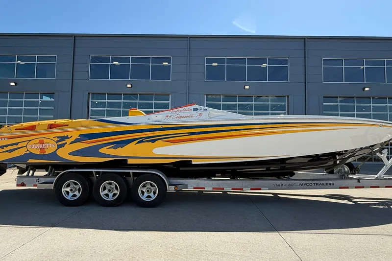 Slide: The Image of 2002 Cigarette 35' Playboy Edition speedboat on trailer, vibrant yellow and blue design. - 36