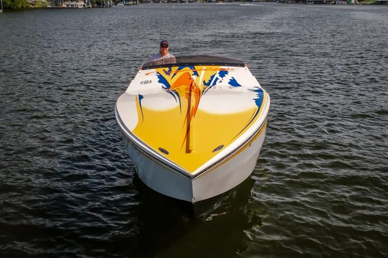 Slide: The Image of 2002 Cigarette 35' Playboy Edition boat with vibrant yellow and blue design on water. - 3
