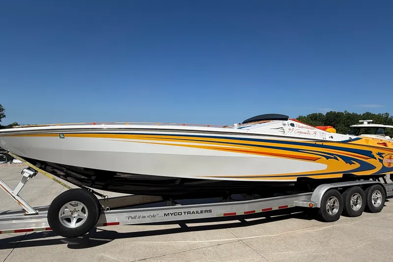 Slide: The Image of 2002 Cigarette 35' Playboy Edition boat on trailer, vibrant yellow and blue design. - 41