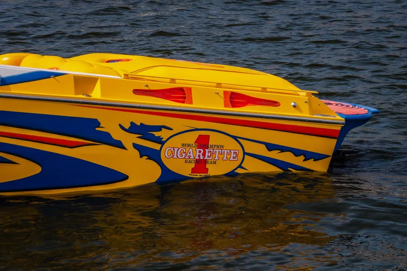 Slide: The Image of 2002 Cigarette 35' Playboy Edition speedboat with vibrant yellow and blue design on water. - 6