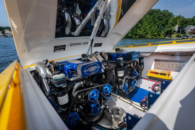 Slide: The Image of 2002 Cigarette 35' Playboy Edition boat engine compartment with dual engines, open hatch, and lake view. - 17