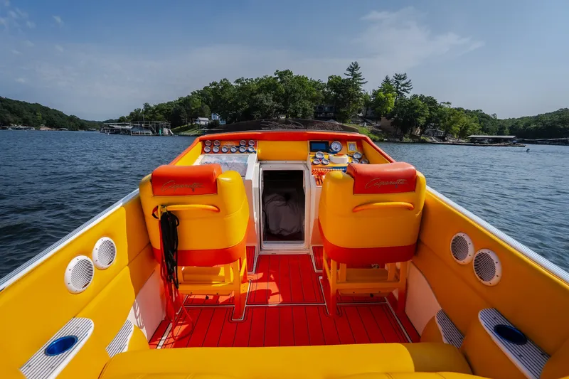 Slide: The Image of 2002 Cigarette 35' Playboy Edition boat interior with vibrant yellow and red seating on a lake. - 18