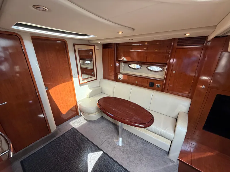 Slide: The Image of The interior cabin of a 2005 Sea Ray 390 DA features an elegant seating area with a wooden table. - 34