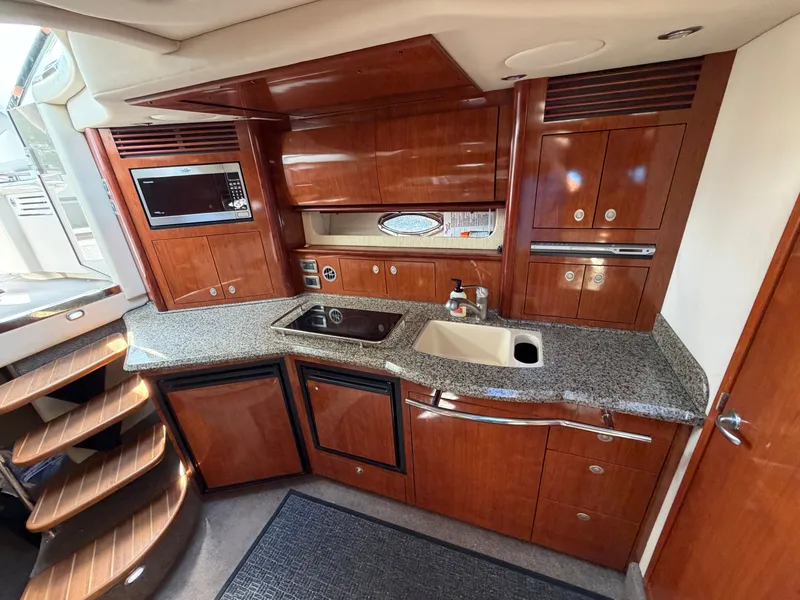 Slide: The Image of The galley of a 2005 Sea Ray 390 DA with wooden cabinets and granite countertop. - 33