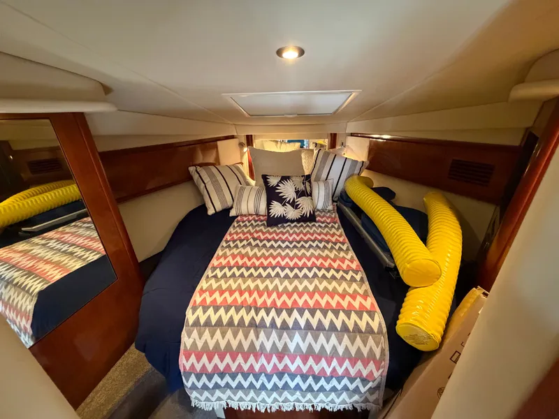 Slide: The Image of The cabin of a 2005 Sea Ray 390 DA with a cozy bed and decorative pillows. - 38