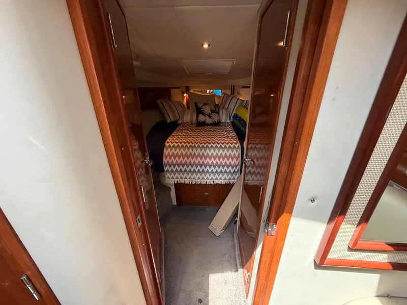 Slide: The Image of The cabin of a 2005 Sea Ray 390 DA with a cozy bed and wooden doors. - 37