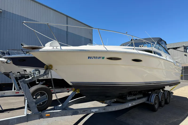 The Image of 1987 Sea Ray 300 Weekender boat on trailer, parked outdoors near a building. - 0