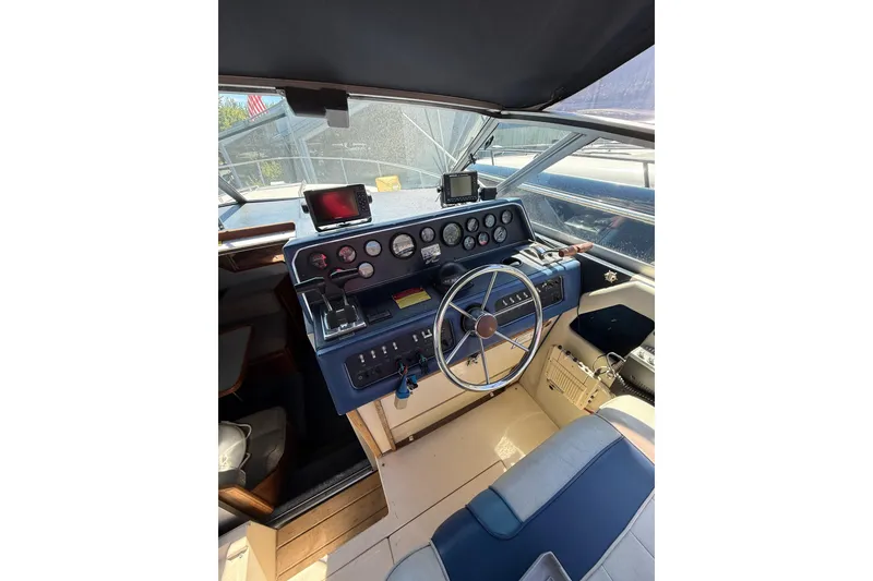 Slide: The Image of 1987 Sea Ray 300 Weekender helm with steering wheel, gauges, and navigation equipment. - 1