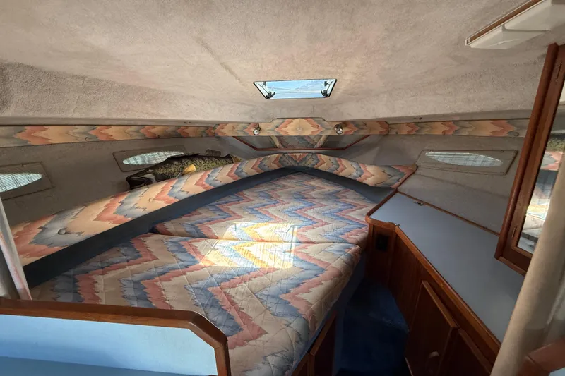 Slide: The Image of Interior cabin of a 1987 Sea Ray 300 Weekender with patterned bedding and wood accents. - 11