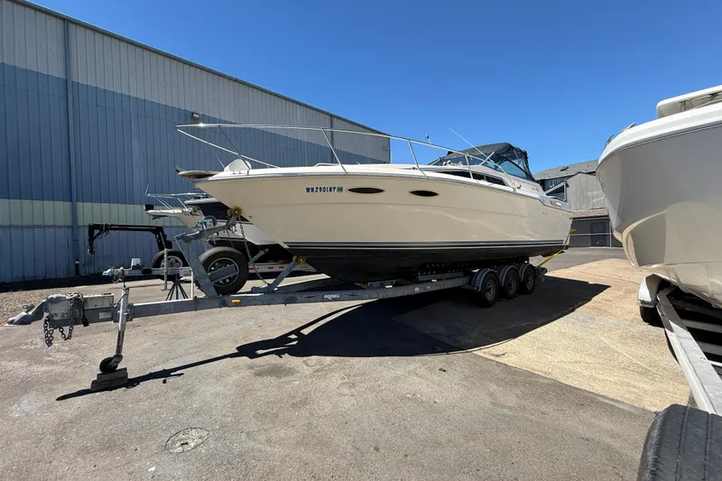 Slide: The Image of 1987 Sea Ray 300 Weekender boat on trailer, parked outdoors near industrial building. - 16