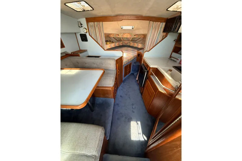 Slide: The Image of Interior of a 1987 Sea Ray 300 Weekender boat, featuring cozy seating and compact kitchen area. - 6
