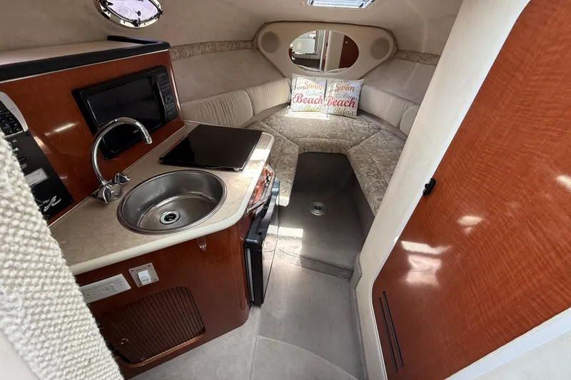 Slide: The Image of 2004 Sea Ray 240 Sundancer cabin interior with kitchenette and cozy seating area. - 12