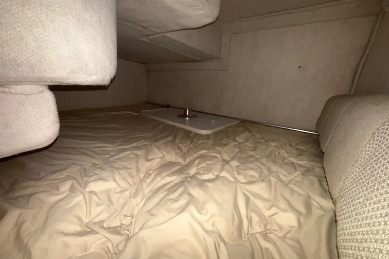 Slide: The Image of Interior cabin of 2004 Sea Ray 240 Sundancer with beige upholstery and compact sleeping area. - 13