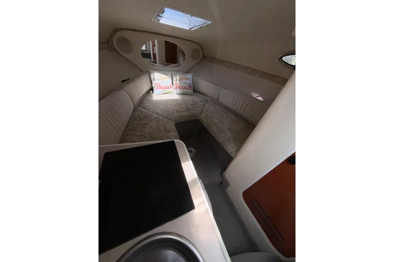 Slide: The Image of Interior cabin of 2004 Sea Ray 240 Sundancer with cozy seating and beach-themed pillows. - 15