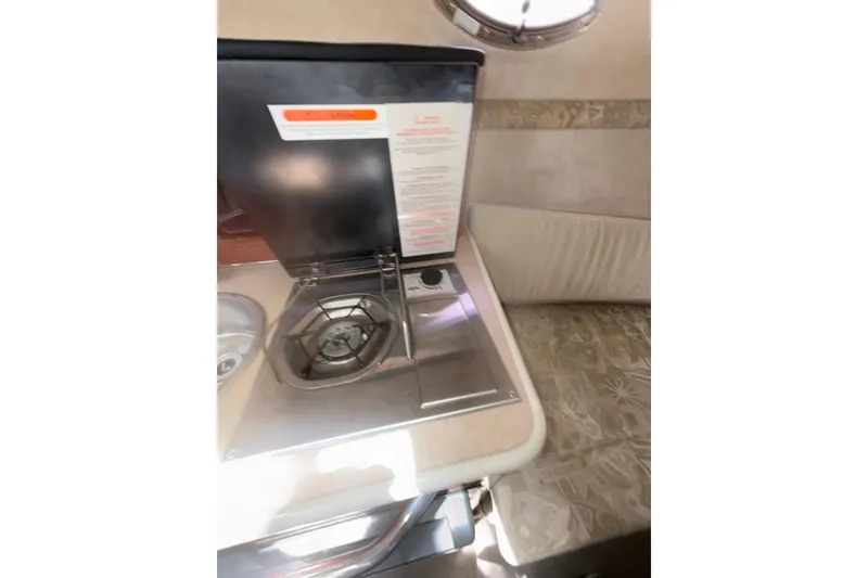 Slide: The Image of 2004 Sea Ray 240 Sundancer interior with compact stove and seating area. - 16