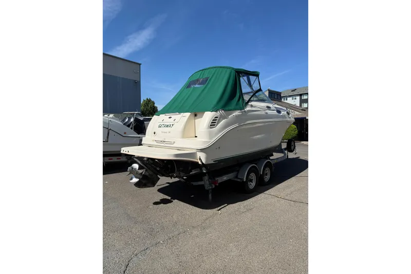 Slide: The Image of 2004 Sea Ray 240 Sundancer boat on trailer with green canopy, parked outdoors. - 3