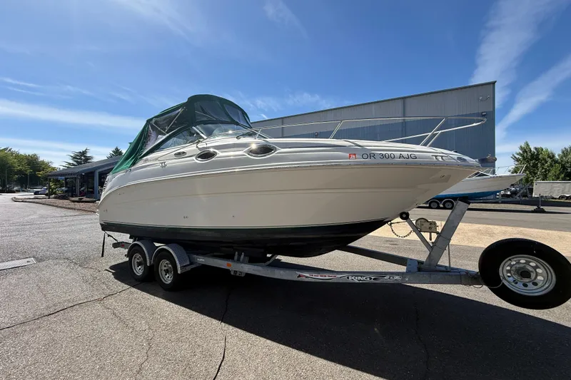 Slide: The Image of 2004 Sea Ray 240 Sundancer boat on trailer, parked outdoors under clear sky. - 4
