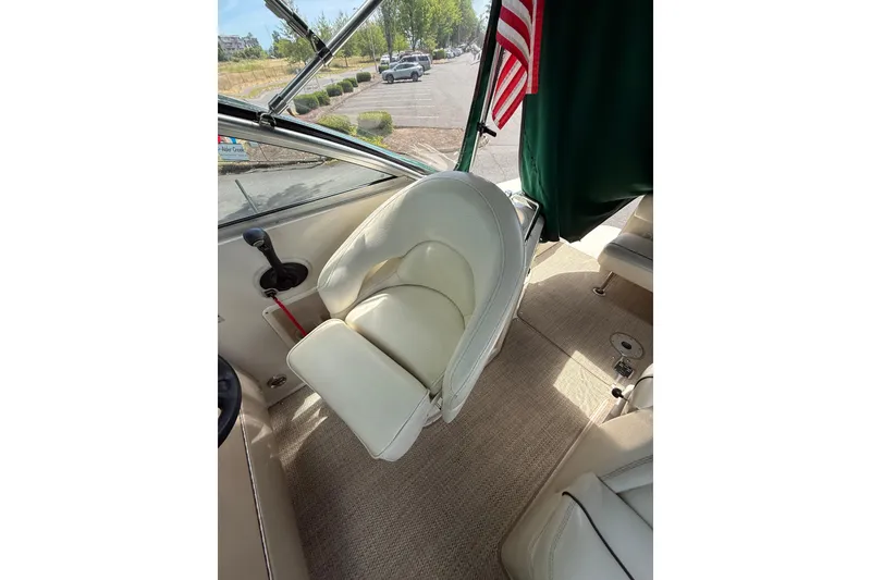 Slide: The Image of Captain's seat on 2004 Sea Ray 240 Sundancer boat, featuring beige upholstery and American flag. - 8