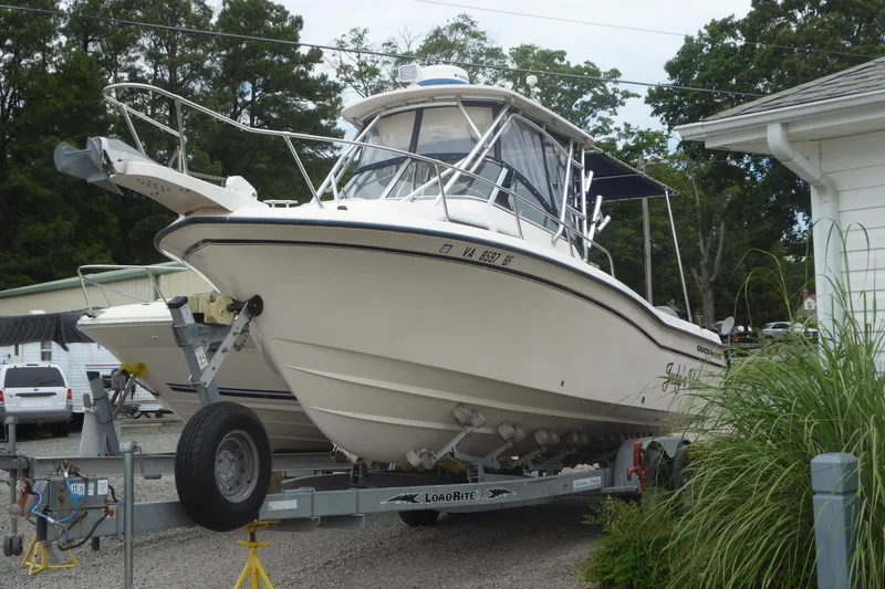 The Image of 2005 Grady-White Journey 258 boat on trailer, parked outdoors near trees and buildings. - 0