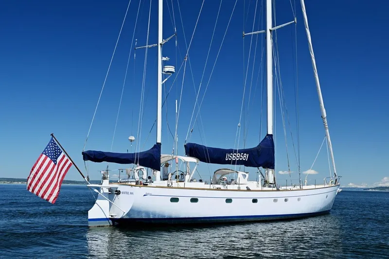Slide: The Image of Sailing yacht Abeking & Rasmussen Tripp 74, 1968, with American flag on calm waters. - 59