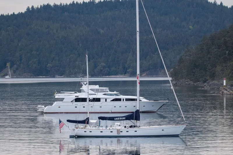 Slide: The Image of Sailboats on calm water with forested hills, featuring a 1968 Abeking & Rasmussen Tripp 74. - 63