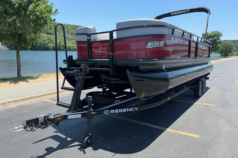 Slide: The Image of 2024 Regency R250DL3 pontoon boat on trailer by a scenic lake. - 2