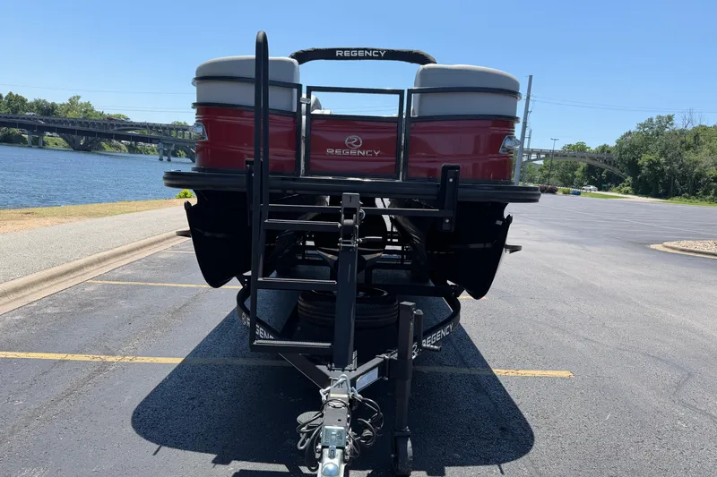 Slide: The Image of 2024 Regency R250DL3 pontoon boat on trailer by a riverside parking lot. - 6