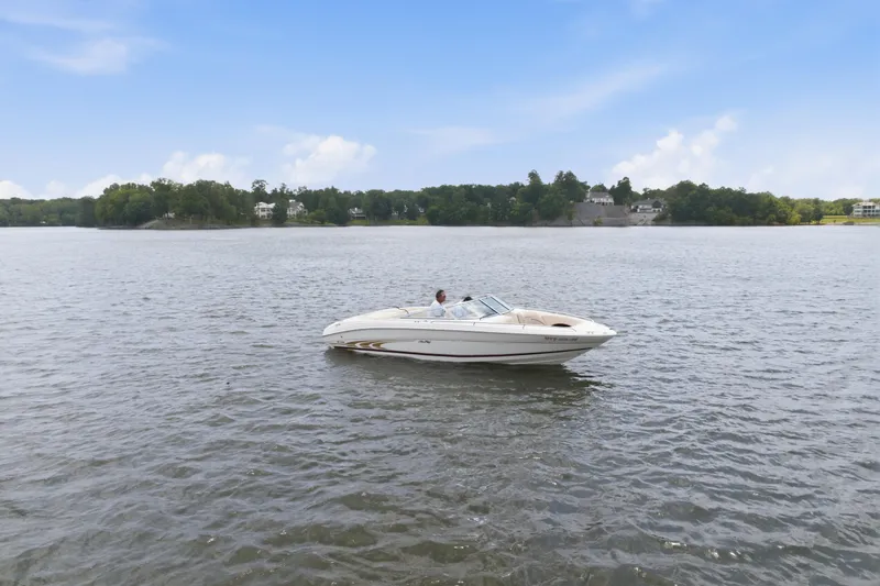 Slide: The Image of 1997 Sea Ray 230 Signature boat cruising on a serene lake under a clear blue sky. - 1
