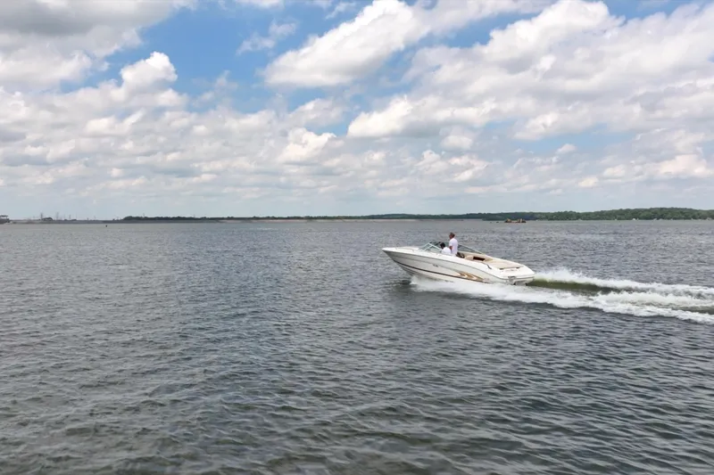 Slide: The Image of A 1997 Sea Ray 230 Signature boat cruising on a lake under a partly cloudy sky. - 10