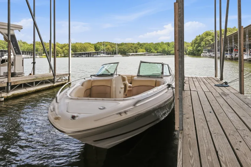 Slide: The Image of 1997 Sea Ray 230 Signature boat docked on a serene lake under a clear blue sky. - 15