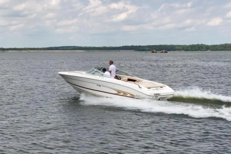Slide: The Image of A 1997 Sea Ray 230 Signature boat cruising on a lake under a partly cloudy sky. - 11