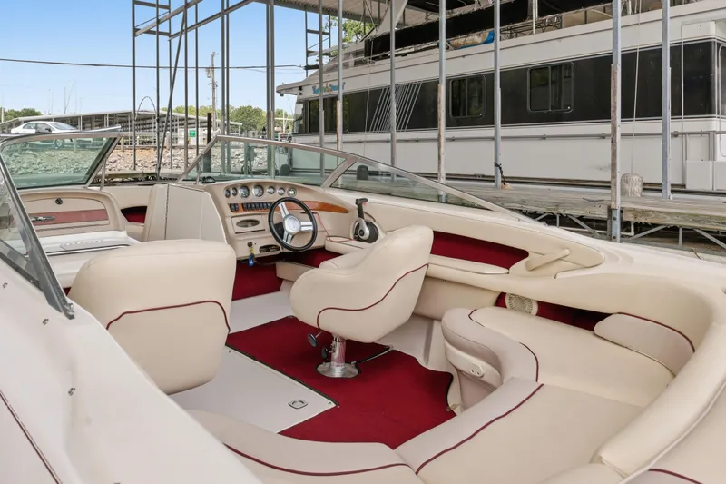 Slide: The Image of 1997 Sea Ray 230 Signature boat interior with cream and red upholstery, docked at marina. - 19
