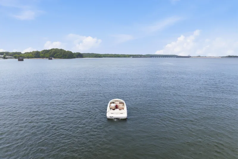 Slide: The Image of A 1997 Sea Ray 230 Signature boat on a calm lake under a clear blue sky. - 2