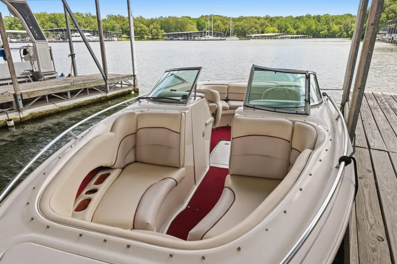 Slide: The Image of 1997 Sea Ray 230 Signature boat with beige seating, docked by a serene lake. - 25