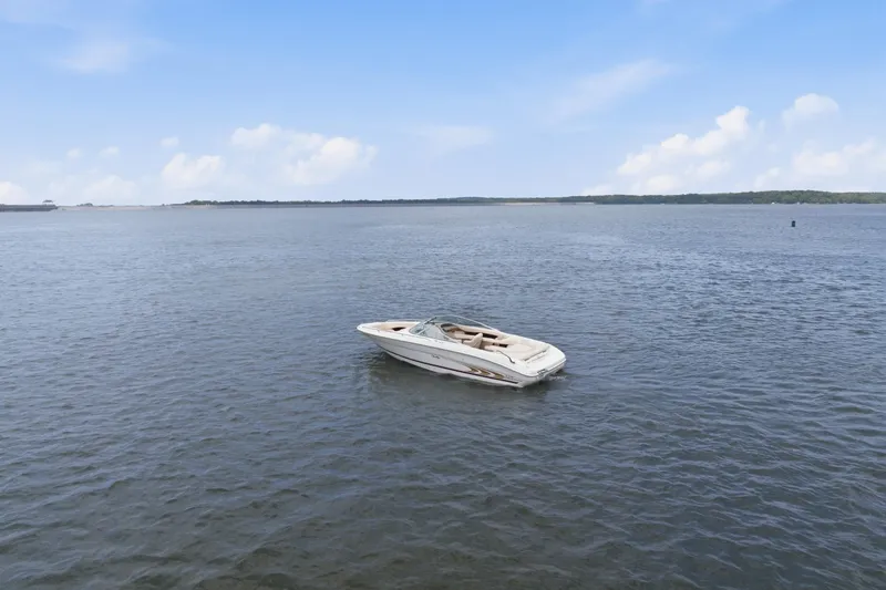 Slide: The Image of 1997 Sea Ray 230 Signature boat floating on calm water under a clear blue sky. - 4