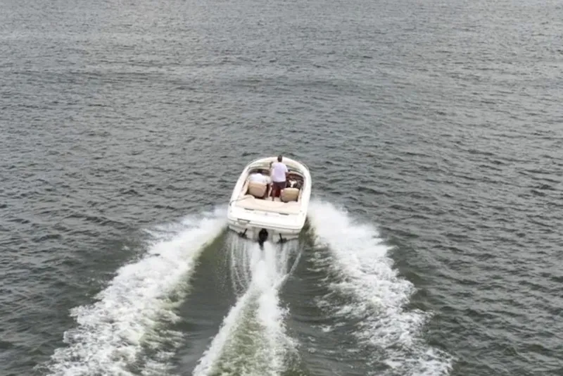 Slide: The Image of 1997 Sea Ray 230 Signature boat cruising on a vast lake under a cloudy sky. - 10