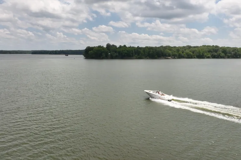 Slide: The Image of A 1997 Sea Ray 230 Signature boat cruising on a calm lake under a cloudy sky. - 7
