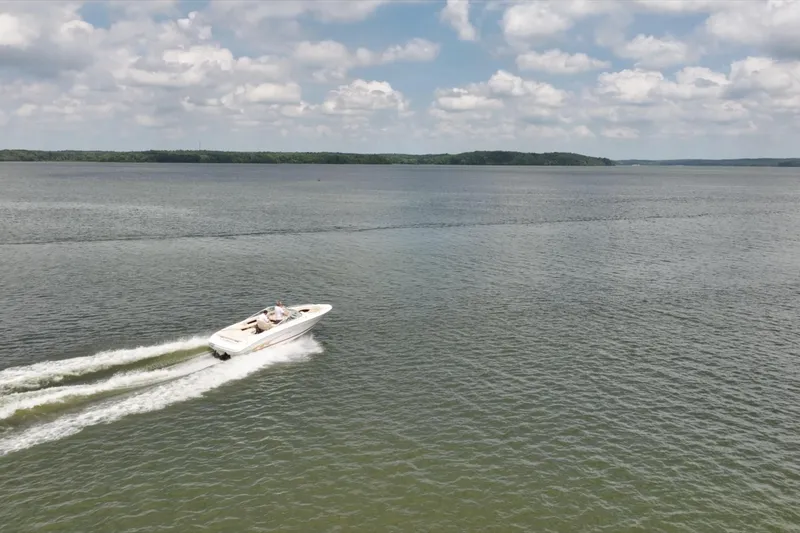 Slide: The Image of 1997 Sea Ray 230 Signature boat cruising on a calm lake under a partly cloudy sky. - 8