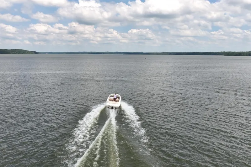 Slide: The Image of 1997 Sea Ray 230 Signature boat cruising on a vast lake under a cloudy sky. - 9