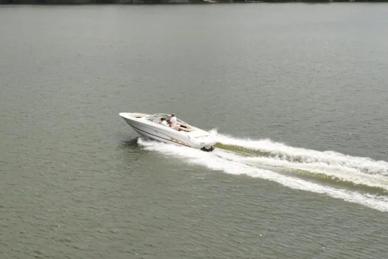 Slide: The Image of A 1997 Sea Ray 230 Signature boat cruising on a calm lake under a cloudy sky. - 8
