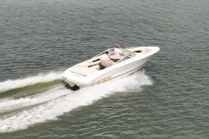 Slide: The Image of 1997 Sea Ray 230 Signature boat cruising on a calm lake under a partly cloudy sky. - 9