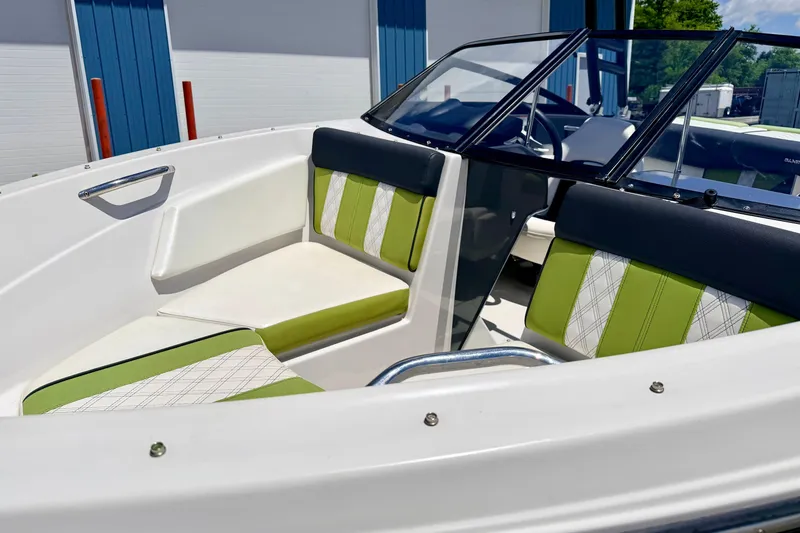 Slide: The Image of 2018 Glastron GT 185 boat interior with green and white seating, docked outdoors. - 14