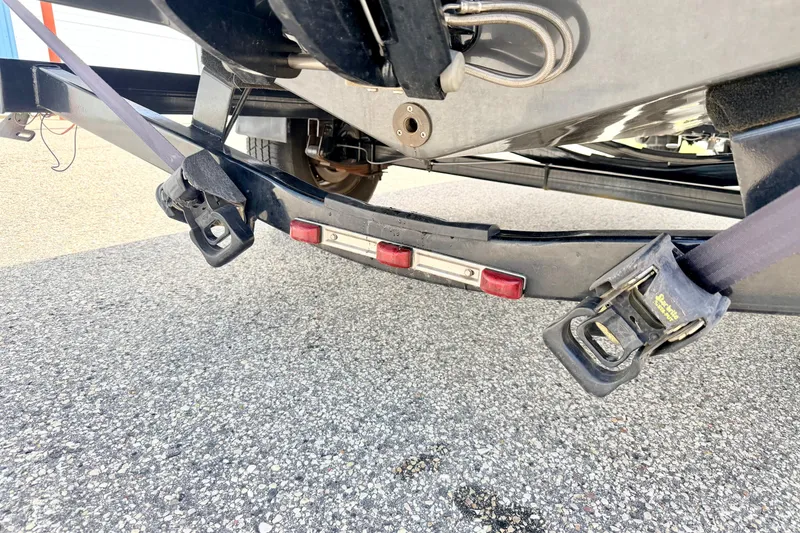 Slide: The Image of Trailer hitch and straps securing a 2018 Glastron GT 185 boat on pavement. - 76