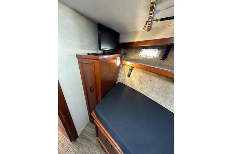 Slide: The Image of 1985 Egg Harbor 33 Sedan cabin interior with bed, TV, and wooden cabinet. - 39
