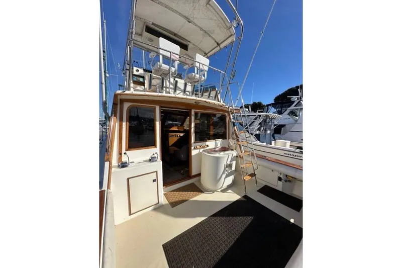 Slide: The Image of 1985 Egg Harbor 33 Sedan boat with upper deck seating and ladder, docked at marina. - 9