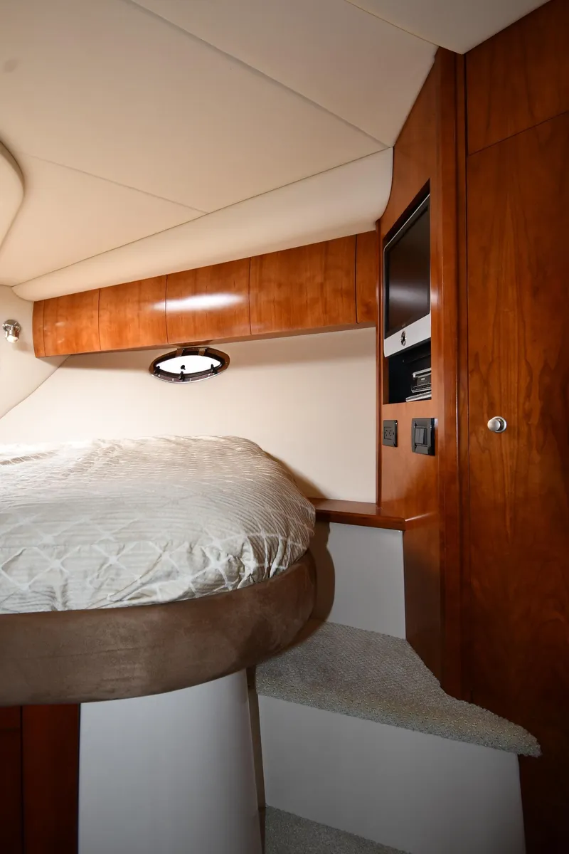 Slide: The Image of Interior of 2010 Cruisers Yachts 390 Sports Coupe, featuring a cozy bed and wooden cabinetry. - 38