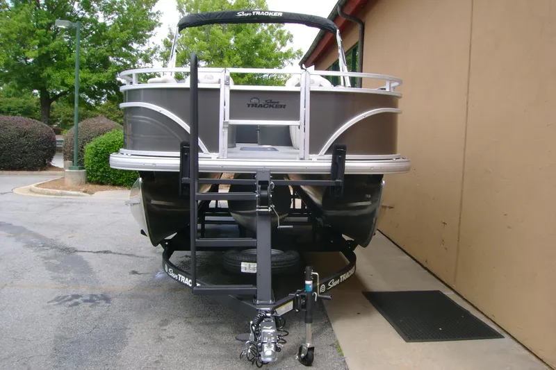 Slide: The Image of 2026 Sun Tracker Fishin' Barge 22 XP3 pontoon boat on trailer, parked outdoors. - 3
